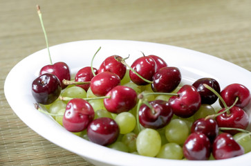 Bowl of Cherry and grape fruits on white background