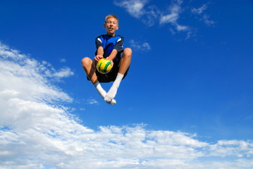 Boy jumping high with ball