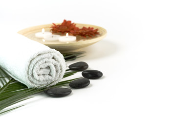 Spa setting with white towel, pebbles, candles and flowers