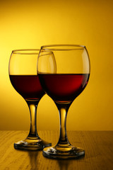Two glasses of red wine over yellow background