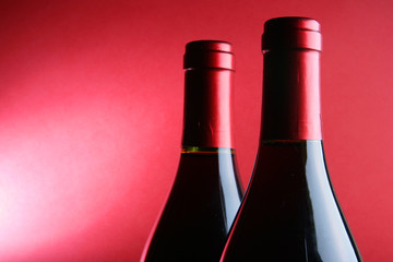 Two corked wine bottles over red background