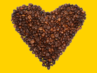 Beans of coffee in the form of heart on a yellow background