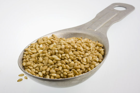 Tablespoon of sesame seeds on white background