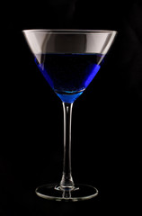 martini glass filled with blue drink shot on black