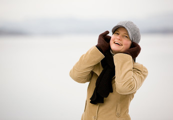 A young woman smiling by the ocean in winter.