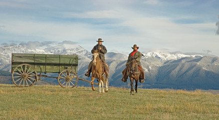 Cowboys on the range, mountain backdrop. 