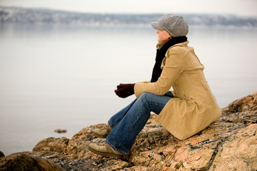 A young woman sitting by the ocean