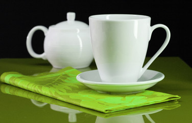 A coffee cup and teapot set on a green table