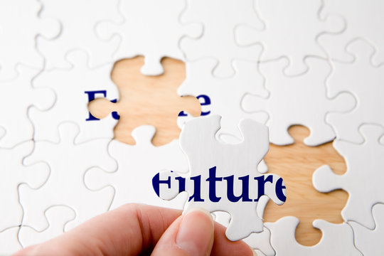Hand holding a piece to complete puzzle with the word "future"