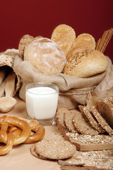 Assortment of baked breads and pretzels with a cup of yoghurt