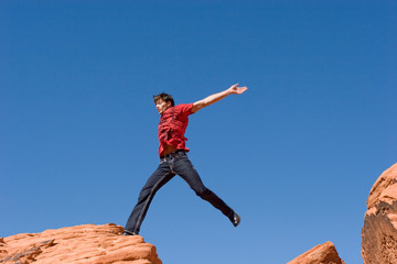 Obraz premium Handsome young man jumping on red rocks