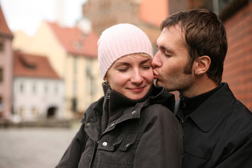 Young couple kissing in an old european town square.