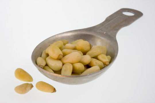 Tablespoon of pine nuts on white