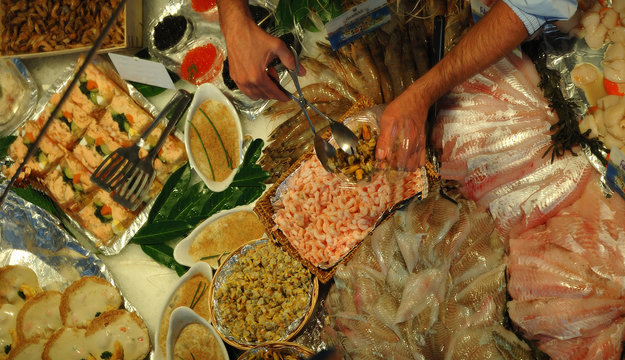 Seafood display with hands of man packaging shrimp.