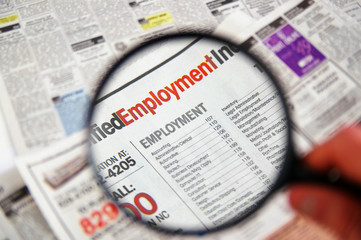 Magnifying glass over a newspaper classified section © zimmytws