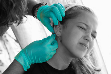 young beautiful girl stand pain during piercing