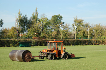 Tractor leveling soccer field using heavy metal lawn roller