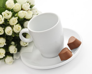 A bunch of flowers, coffee-cup and a pair heart of chocolate.