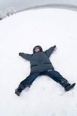 Fototapeta na wymiar The boy lays on a snow