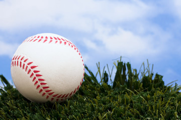 Baseball sitting on grass with sky background