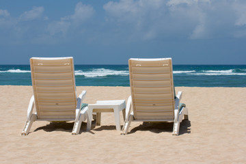 Two sun beach chairs on shore near ocean