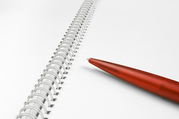 Open, blank spiral notebook with red plastic pen.