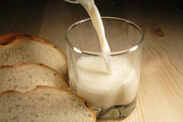 Glass of milk and incised bread stick on wooden plate