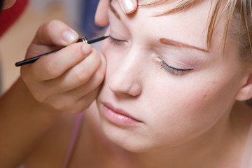 The young woman directs a make-up in the morning before wedding
