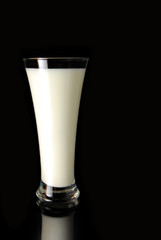 An isolated glass of milk with a strong reflection