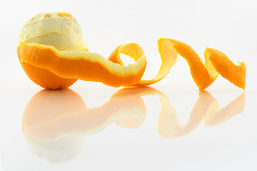 Orange with peeled skin reflecting in glass surface.