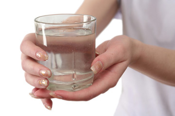 Glass of water in female hands on a white background