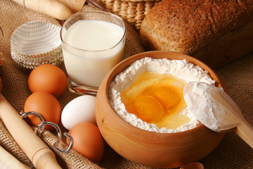 Rolling pin with scattered flour and a bowl of flour with eggs.