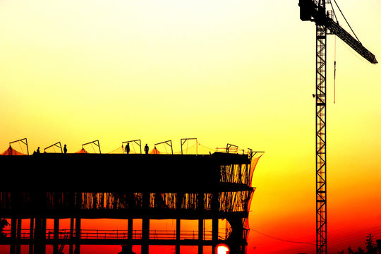 Workers on a construcion site at sunset