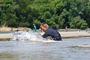 Fototapeta na wymiar a boy sitting splashes the water at the beach