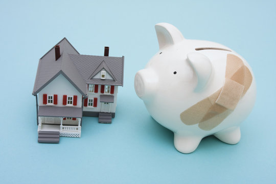 Piggy bank with adhesive bandage and house on blue background