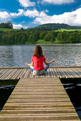 Fototapeta na wymiar Kobieta medytacji na przystani nad jeziorem