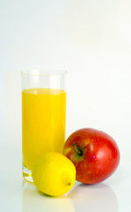 Glass of orange juice, lemon and apple on white background