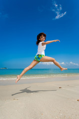 young beautiful girl jumping happily at the beach