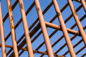 Rusty cage detail painted in red against the sky