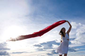 Frau winkt mit rotem Tuch vor blauem Himmel