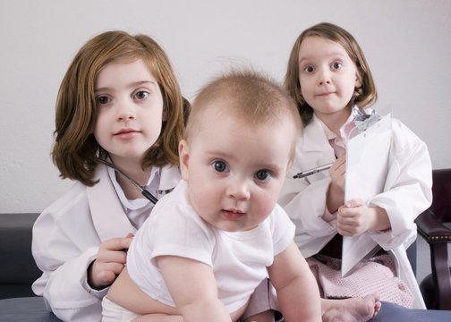 Three little girls playing doctor (high-key).