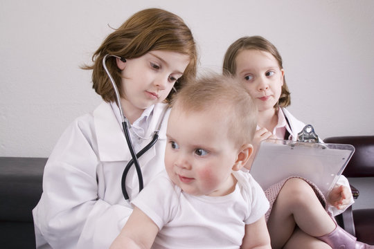 Little girl listening to a baby with a stethoscope.