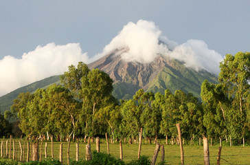An active volcano looms  over rich, fertile fields below