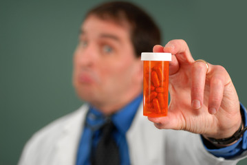 Doctor with questioning look showing bottle of pills - obrazy, fototapety, plakaty