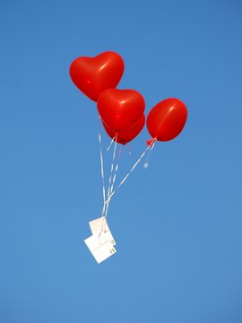 Rote herzförmige Luftballons mit Postkarte, blauer Himmel