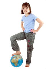 A young girl with foot on the globe against white background