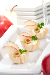 Three mini fillo shells filled with cream cheese, pears, olives