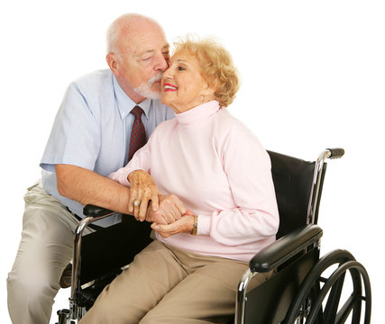 Affectionate senior husband giving his disabled wife a kiss 