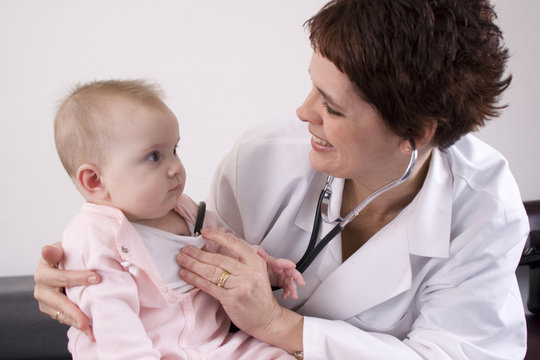Female physician listening to a baby with a stethoscope.