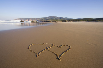 tho heart shapes writed on the beach sand